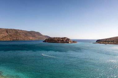 Deniz ve dağların panoramik görüntüsü ve bir drondan çekilen turkuaz su üzerindeki gemiler.