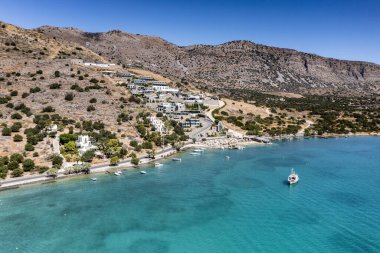 Deniz ve dağların panoramik görüntüsü ve bir drondan çekilen turkuaz su üzerindeki gemiler.