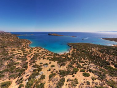 Deniz ve dağların panoramik görüntüsü ve bir drondan çekilen turkuaz su üzerindeki gemiler.