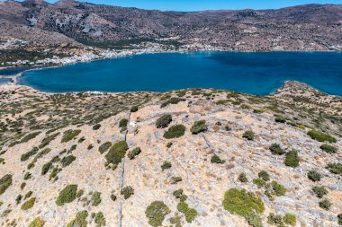 Deniz ve dağların panoramik görüntüsü ve bir drondan çekilen turkuaz su üzerindeki gemiler.