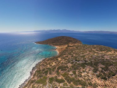 Deniz ve dağların panoramik görüntüsü ve bir drondan çekilen turkuaz su üzerindeki gemiler.