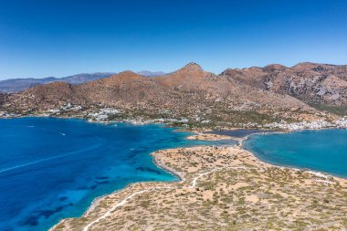 Deniz ve dağların panoramik görüntüsü ve bir drondan çekilen turkuaz su üzerindeki gemiler.