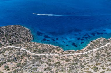 Deniz ve dağların panoramik görüntüsü ve bir drondan çekilen turkuaz su üzerindeki gemiler.