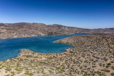 Deniz ve dağların panoramik görüntüsü ve bir drondan çekilen turkuaz su üzerindeki gemiler.