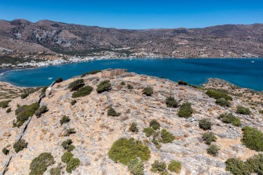 Deniz ve dağların panoramik görüntüsü ve bir drondan çekilen turkuaz su üzerindeki gemiler.
