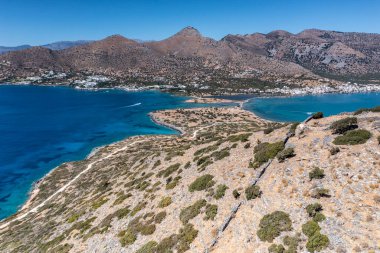 Deniz ve dağların panoramik görüntüsü ve bir drondan çekilen turkuaz su üzerindeki gemiler.