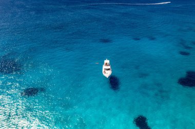Deniz ve dağların panoramik görüntüsü ve bir drondan çekilen turkuaz su üzerindeki gemiler.