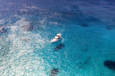 Deniz ve dağların panoramik görüntüsü ve bir drondan çekilen turkuaz su üzerindeki gemiler.