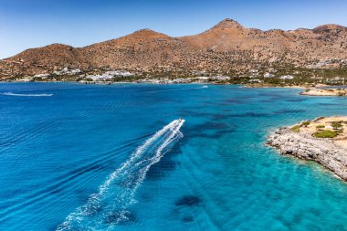 Deniz ve dağların panoramik görüntüsü ve bir drondan çekilen turkuaz su üzerindeki gemiler.