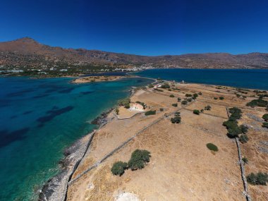 Deniz ve dağların panoramik görüntüsü ve bir drondan çekilen turkuaz su üzerindeki gemiler.