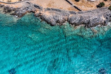 Deniz ve dağların panoramik görüntüsü ve bir drondan çekilen turkuaz su üzerindeki gemiler.