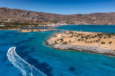 Deniz ve dağların panoramik görüntüsü ve bir drondan çekilen turkuaz su üzerindeki gemiler.