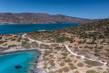 Deniz ve dağların panoramik görüntüsü ve bir drondan çekilen turkuaz su üzerindeki gemiler.