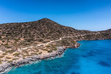 Deniz ve dağların panoramik görüntüsü ve bir drondan çekilen turkuaz su üzerindeki gemiler.