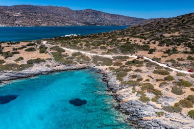 Deniz ve dağların panoramik görüntüsü ve bir drondan çekilen turkuaz su üzerindeki gemiler.