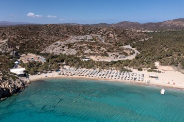 Deniz ve dağların panoramik görüntüsü ve bir drondan çekilen turkuaz su üzerindeki gemiler.