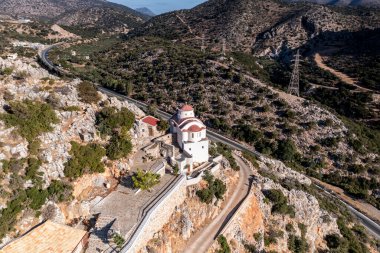 Beyaz taş kilisenin panoramik görüntüsü, dağların arka planına ve Girit 'in zeytinliklerine karşı bir dron tarafından filme alındı. 