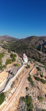 Beyaz taş kilisenin panoramik görüntüsü, dağların arka planına ve Girit 'in zeytinliklerine karşı bir dron tarafından filme alındı. 