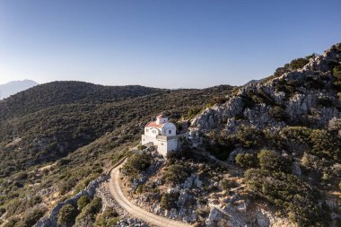 Beyaz taş kilisenin panoramik görüntüsü, dağların arka planına ve Girit 'in zeytinliklerine karşı bir dron tarafından filme alındı. 