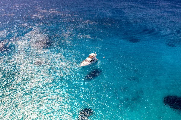 Deniz ve dağların panoramik görüntüsü ve bir drondan çekilen turkuaz su üzerindeki gemiler.
