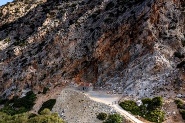 Beyaz taş kilisenin panoramik görüntüsü, dağların arka planına ve Girit 'in zeytinliklerine karşı bir dron tarafından filme alındı. 