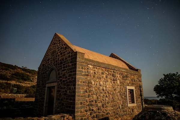 starry sky over mountains, sea and old buildings on the island of Crete