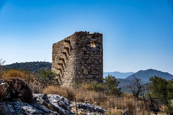 ancient stone mills and their ruins on the slopes of the mountains in Crete on a sunny day