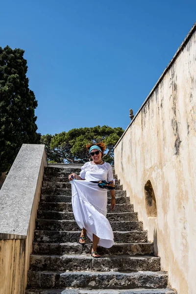 woman in white on the background of the sea mountains blue sky and ancient buildings on the island of Crete