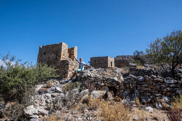 a man in green against the background of ancient dilapidated mills on the island of Crete