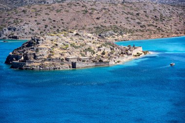 Deniz kıyısına bakan manzara ve ufukta bir deniz gemisi.