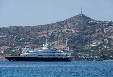 Deniz kıyısına bakan manzara ve ufukta bir deniz gemisi.