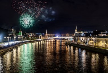 Gece nehrinin üzerinde havai fişekler. Suyun üzerinde yüzen motorlu gemiler ve eski Kremlin. 