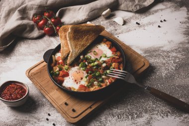 Shakshouka dökme demir tavada. Sebzeli yumurta ve tost..