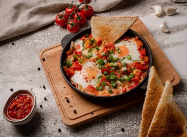 Shakshouka dökme demir tavada. Sebzeli yumurta ve tost..