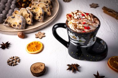 Komik bardakta sıcak kış içeceği, Noel kakaosu ahşap tahtanın üzerinde kurumuş meyve ve fındıklı. Geleneksel Alman pastası. Kartpostal ve bayram tebriği kavramı..