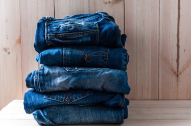 Birçok kot pantolon yığınının ahşap arka plan üzerinde kapat