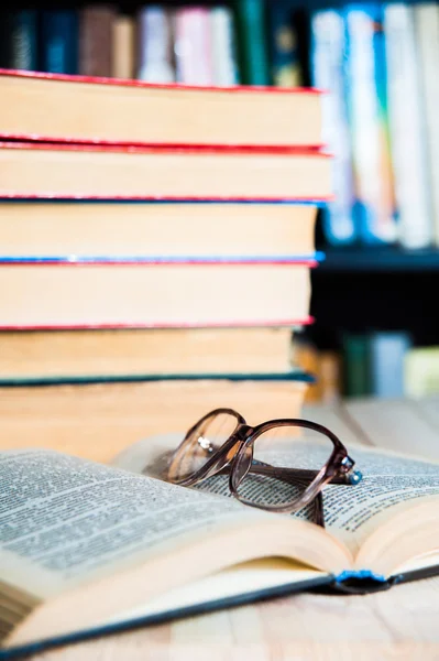 Livro e óculos na mesa na biblioteca — Fotografia de Stock