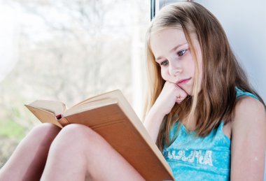 Şirin kız öğrenci pencerede otururken okuma