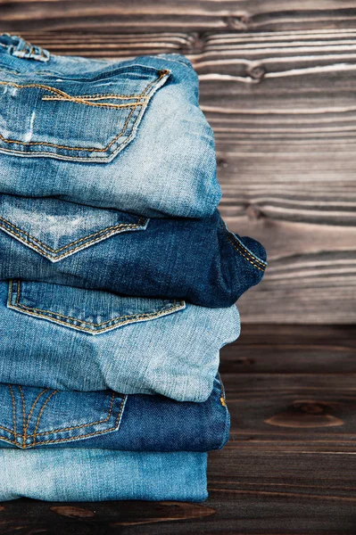 Pilha de roupas de jeans no fundo de madeira . — Fotografia de Stock