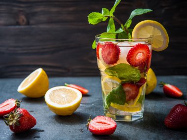 Çilek limonata ve malzemeler - çilek, limon, koyu taş arka plan.