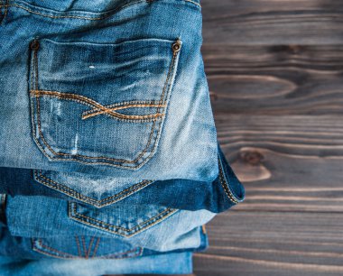 ahşap arka plan üzerinde çeşitli tonları mavi jeans yığını