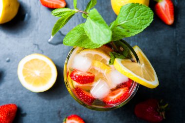 Çilek limonata ve malzemeler - çilek, limon, koyu taş arka plan.
