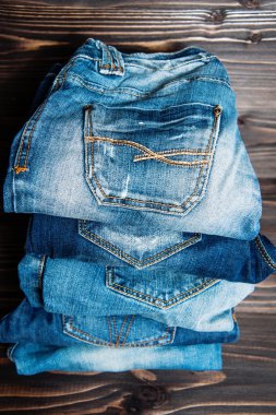 ahşap arka plan üzerinde çeşitli tonları mavi jeans yığını