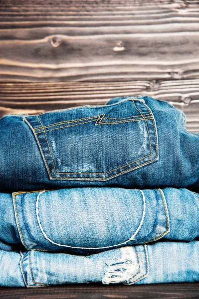 Roupas da moda. pilha de jeans em fundo de madeira — Fotografia de Stock