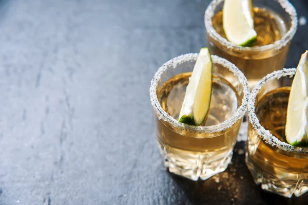 Tequila con cal y sal marina sobre mesa negra —  Fotos de Stock