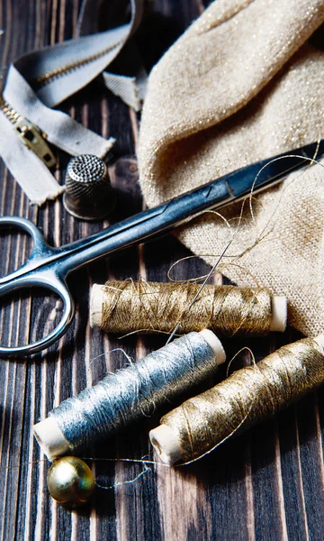 Sewing textile or cloth. Scissors reel of thread, and golden fabric. — Stock Photo, Image