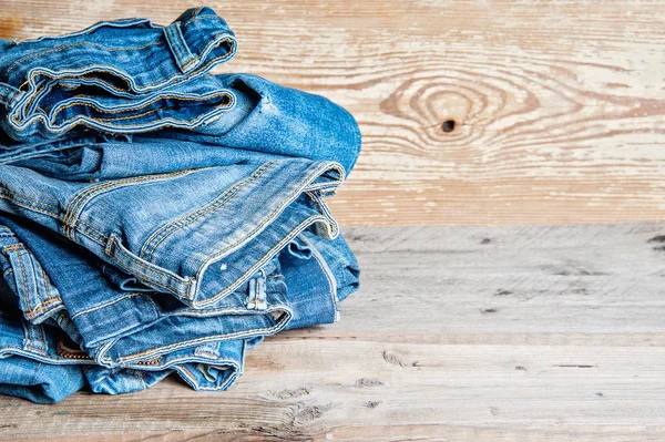 Jeans empilhados em um fundo de madeira — Fotografia de Stock