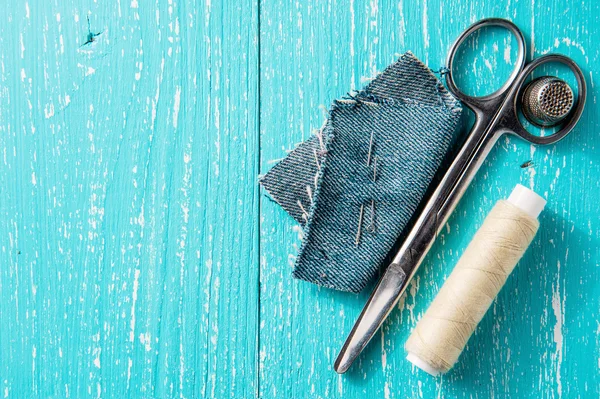 Kit de costura de fios, tesoura e agulha em jeans backround de madeira — Fotografia de Stock