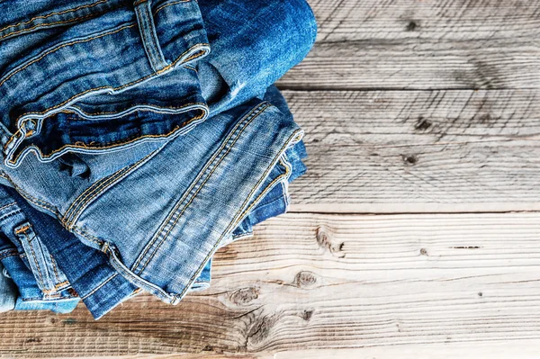 Jeans empilhados em um fundo de madeira — Fotografia de Stock