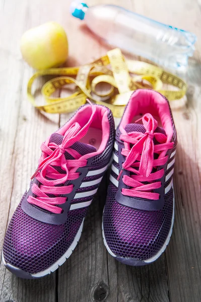 Sport shoes, water, apple, centimeter on wooden background — Stock Photo, Image